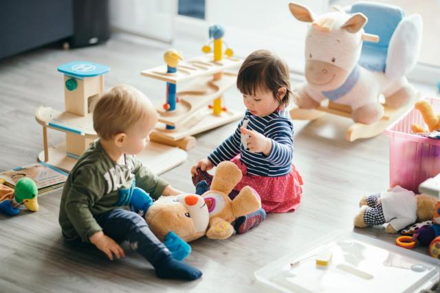 little girl and boy playing with toys by the home 